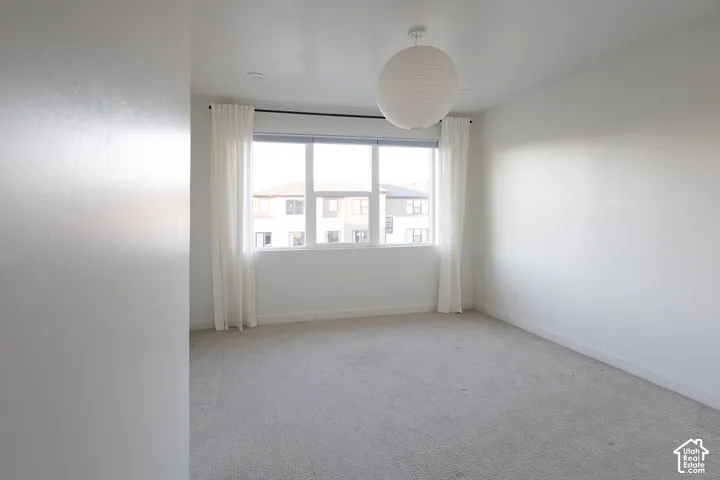 Neutral interior space featuring carpeted flooring, large triple-pane window, and spherical pendant lighting