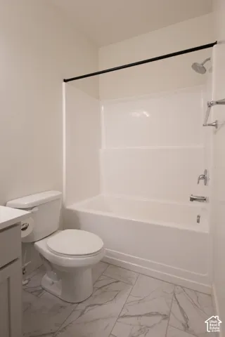 Bathroom featuring a white molded tub-and-shower surround, chrome fixtures, a matte black shower curtain rod, and stone-finish floor tile