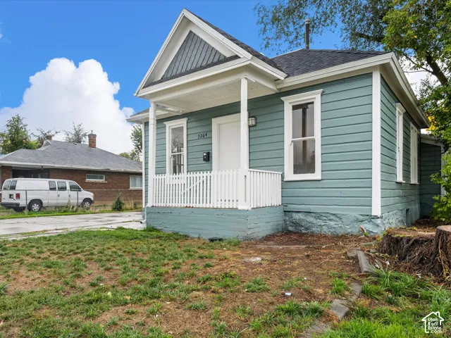 Exterior featuring horizontal siding, a gabled roofline with decorative shake accents, a covered front porch with white picket railing, and a masonry foundation