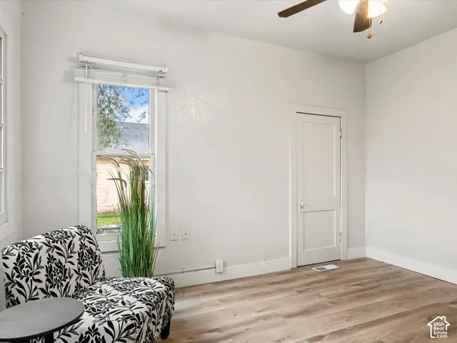 Neutral walls, wood-finish flooring, two-panel interior door, and ceiling fan with integrated lighting