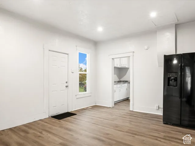 Wood-finish flooring, recessed lighting, double-door refrigerator, and classic interior door and window casing