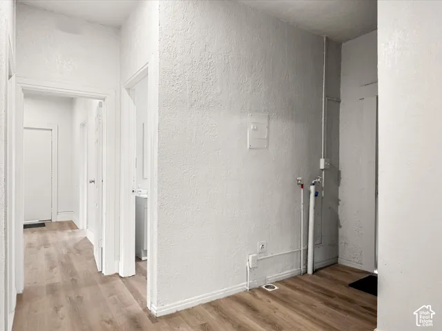 Utility area featuring wood-finish flooring, dedicated water supply lines, and electrical connections