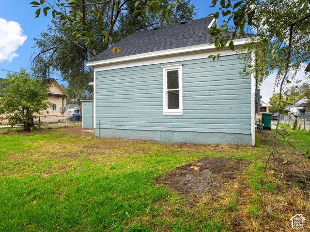 Exterior elevation featuring lap siding, an asphalt shingle roof, a vertical rectangular window, and a fenced backyard