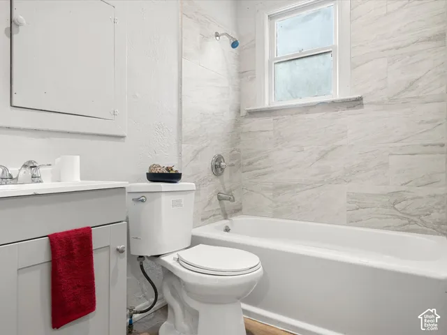 Bathroom featuring a vanity with a white countertop, large-format tile shower surround, and integrated bathtub