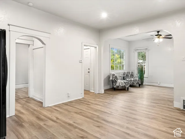 Interior featuring wood-finish flooring, arched architectural detailing, multi-pane windows, and a ceiling fan with light fixture