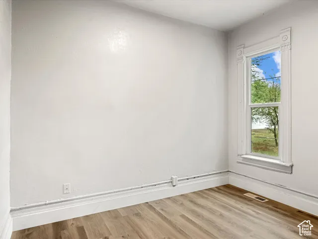 Interior space featuring wood-finish flooring, smooth wall surfaces, and a double-hung window encased in classic decorative millwork