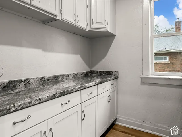 White cabinetry with silver-tone hardware, stone-finish countertops, and wood-finish flooring