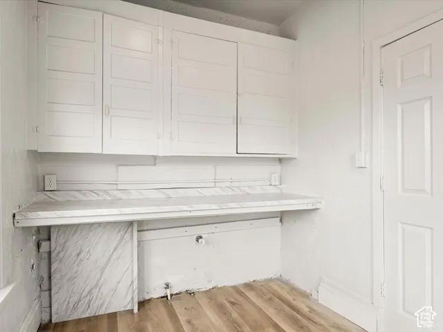 Wall-mounted shaker-style cabinetry, solid-surface countertop with marbled finish, and wood-finish flooring