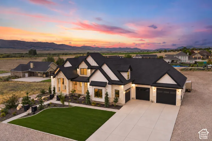 Multi-gabled exterior featuring stone and siding finishes, three-car garage, concrete driveway, and expansive mountain scenery