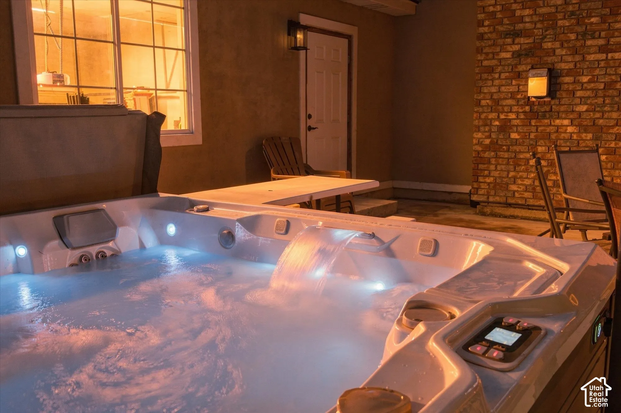 Built-in spa with integrated waterfall feature, exterior brick masonry detailing, and flush-mounted wall lighting
