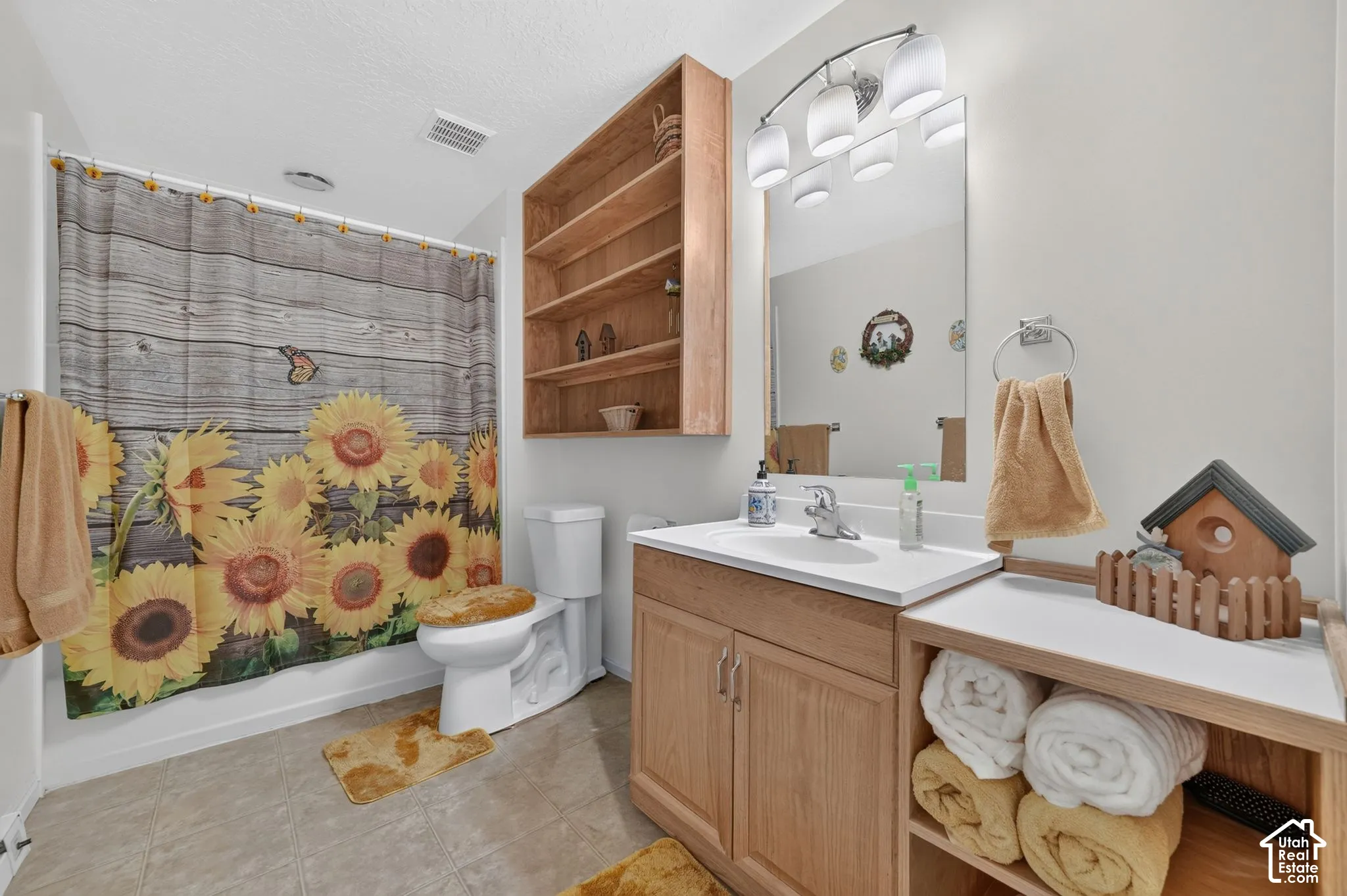 Bathroom featuring a wood-finish vanity with an integrated basin, wall-mounted wood shelving unit, recessed mirror, and multi-light vanity fixture