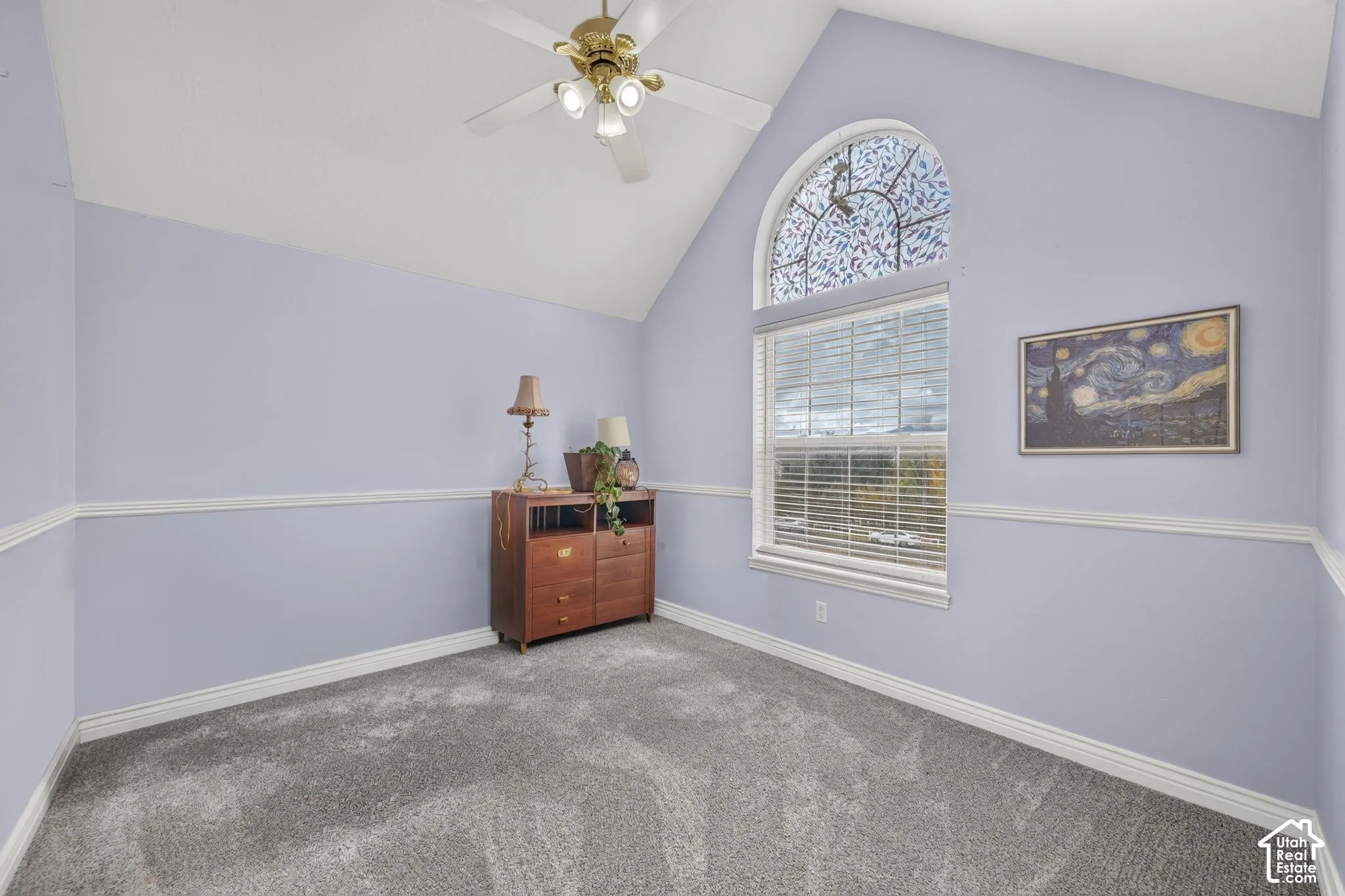 Vaulted ceilings, arched decorative window with leaded glass detail, wall chair rail molding, and neutral carpeting