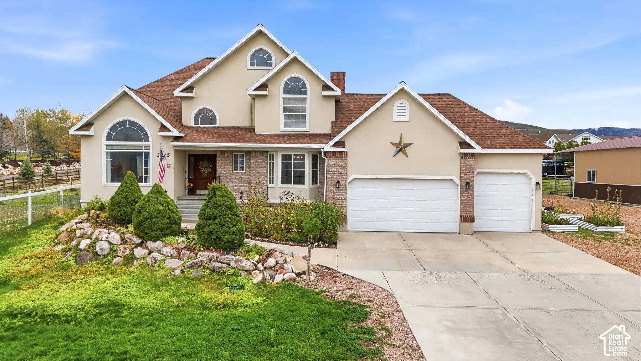 Multi-level exterior featuring stucco siding, brick accents, arched window detailing, a shingled roof, and a three-car garage