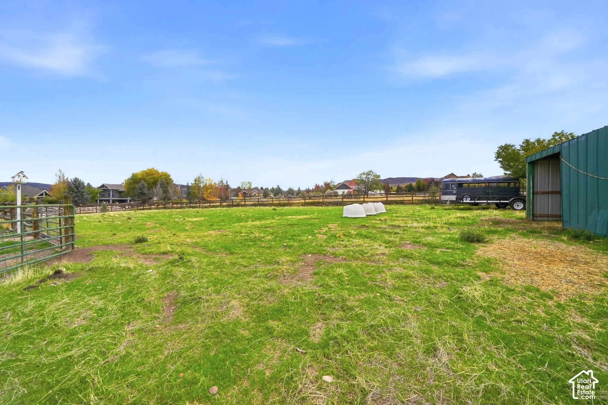 Expansive pasture featuring perimeter metal fencing and a green metal-sided structure