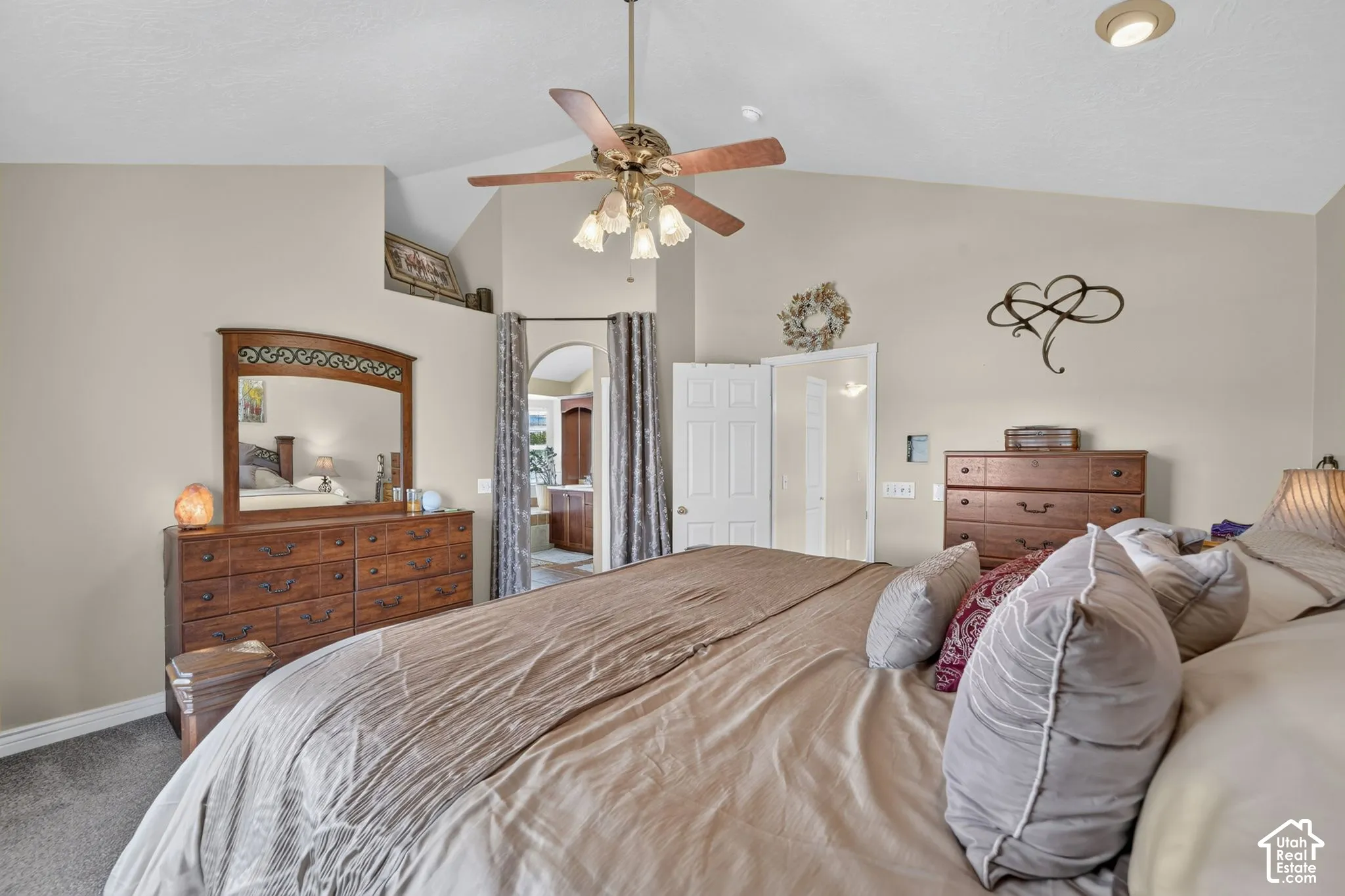 Vaulted ceilings featuring a central multi-blade ceiling fan with integrated lighting and a prominent recessed arched entry
