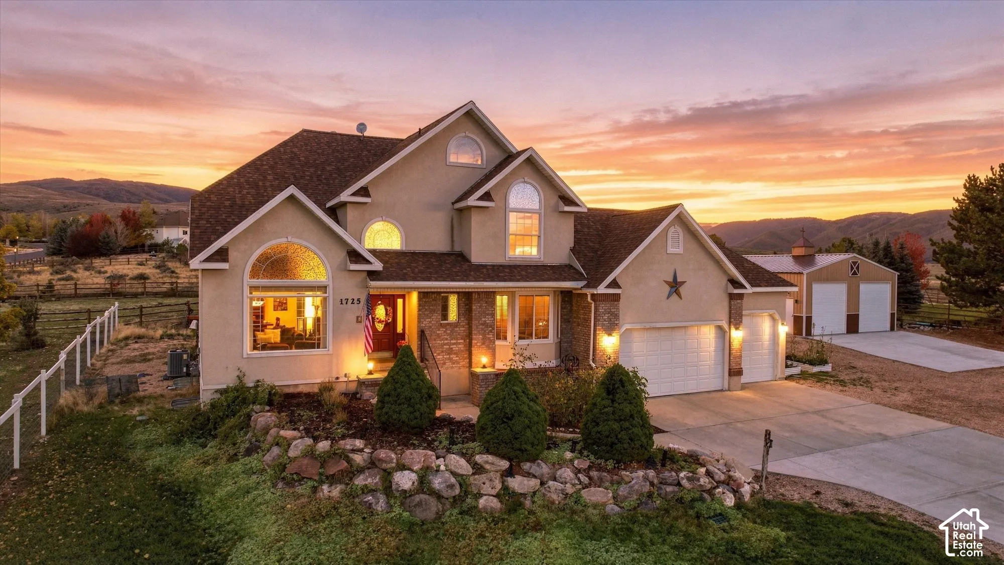 Multi-level residence featuring stucco and brick exterior, arched windows, attached multi-car garage, and a detached structure with concrete driveway
