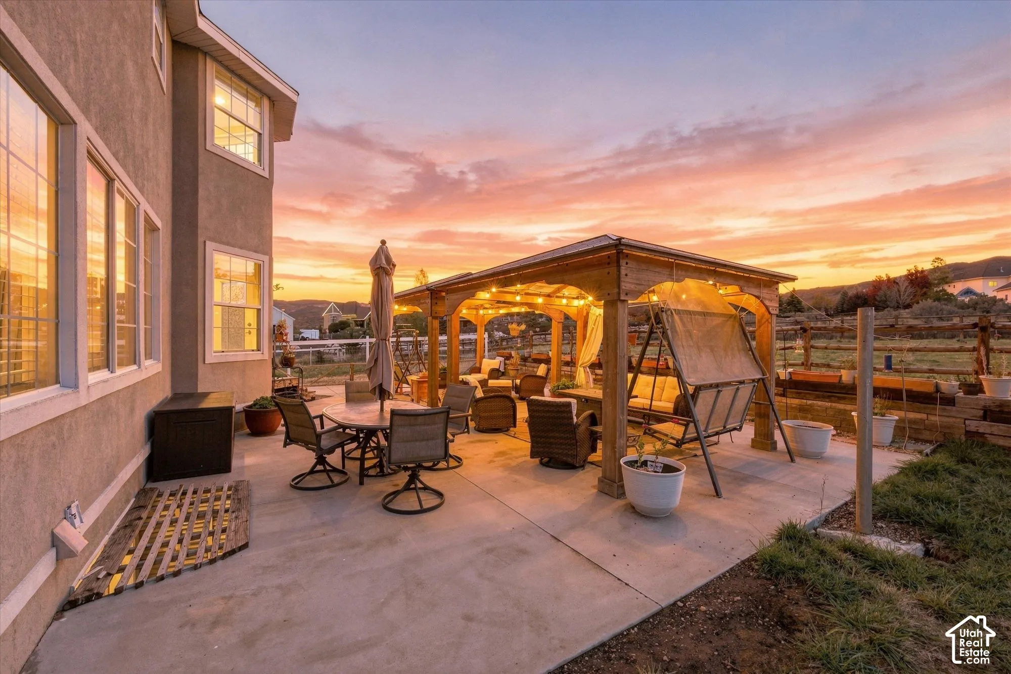 Rear concrete patio featuring a wooden pergola, stucco exterior wall, and mountain backdrop