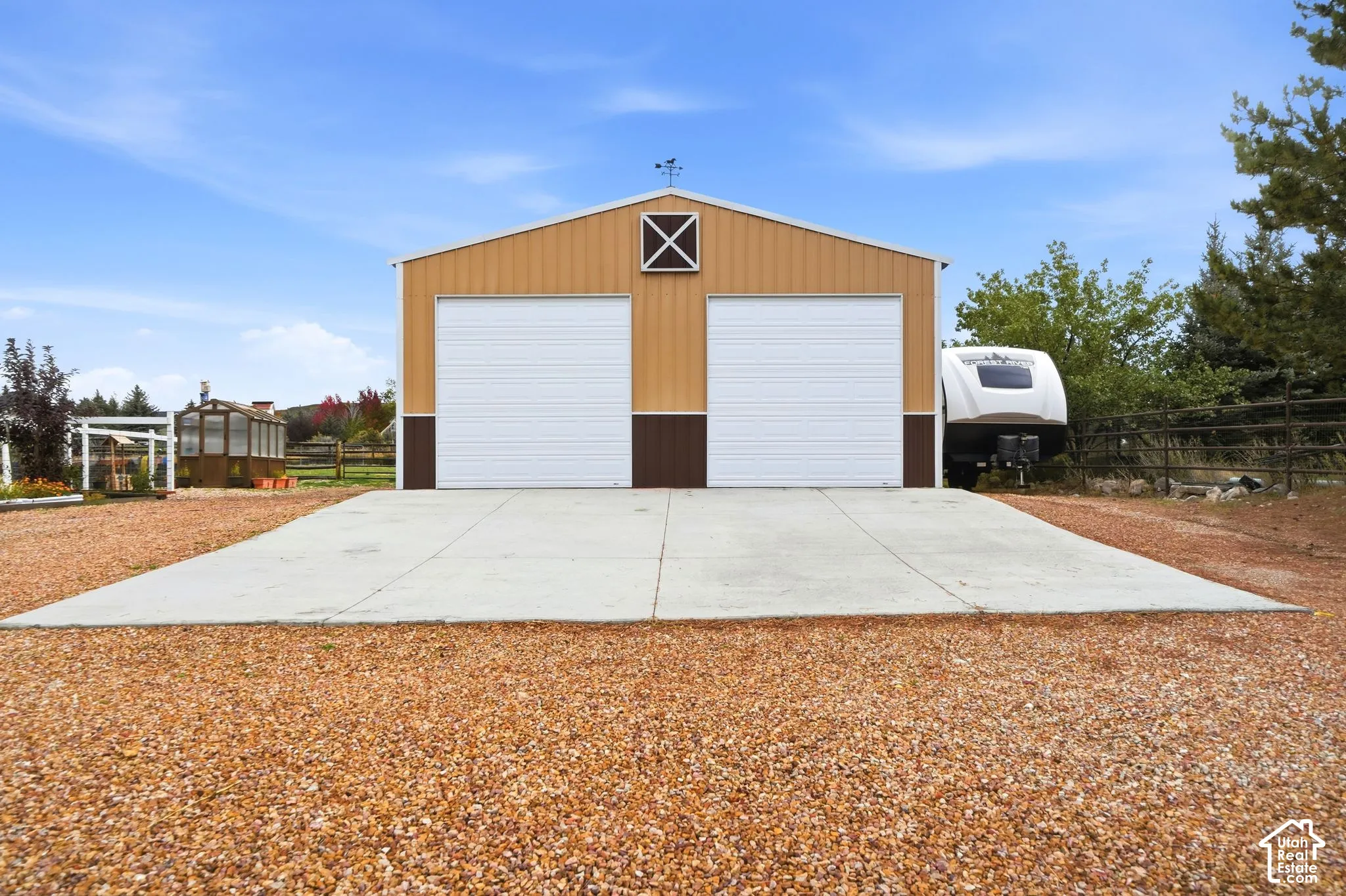 Detached two-car garage featuring metal siding, a concrete apron, and a gable roof with a decorative cupola