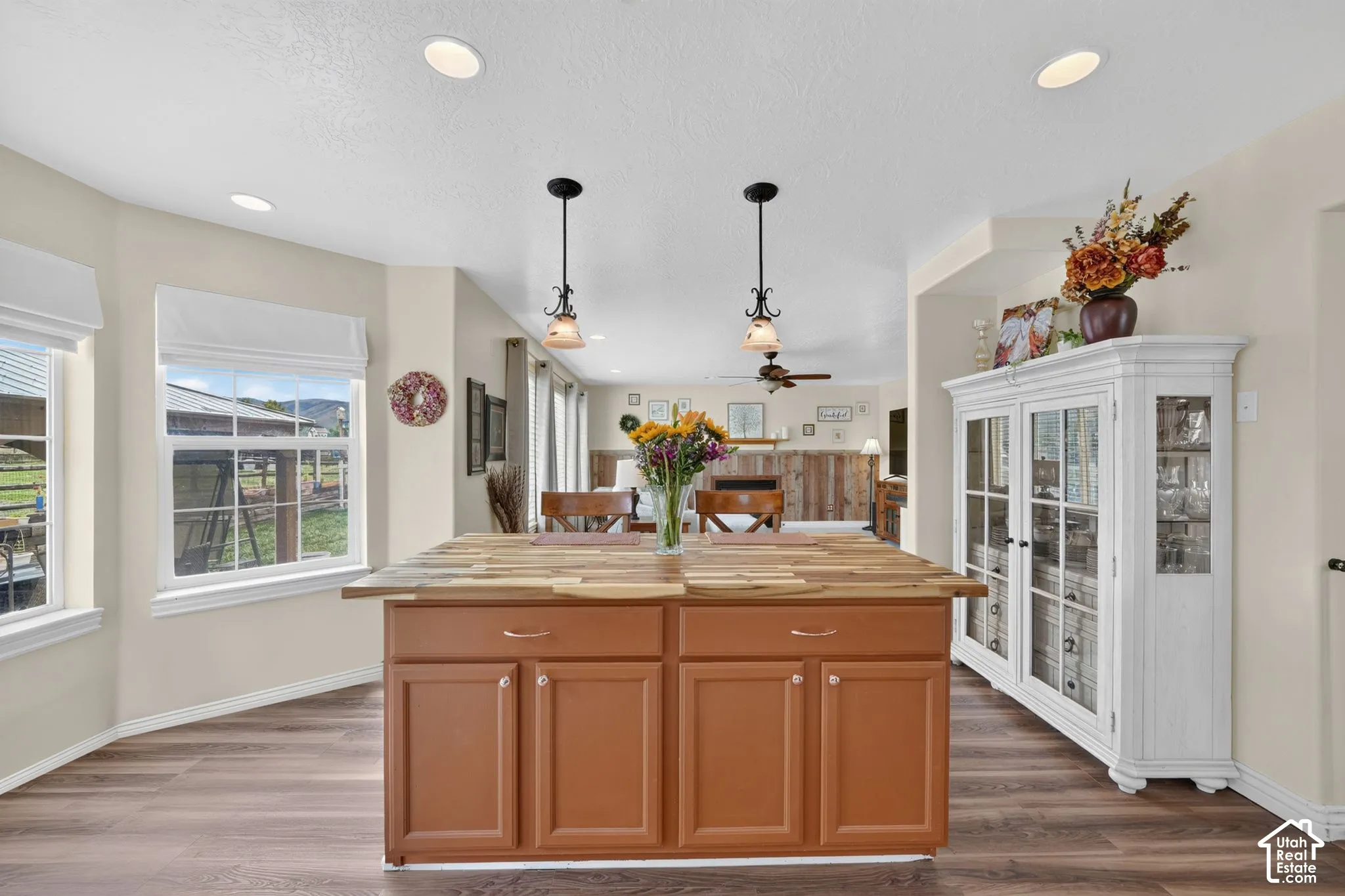 Kitchen featuring a center island with a wood countertop, dual overhead pendant lighting, recessed ceiling lights, wood-finish flooring, and built-in cabinetry with glass-paneled doors