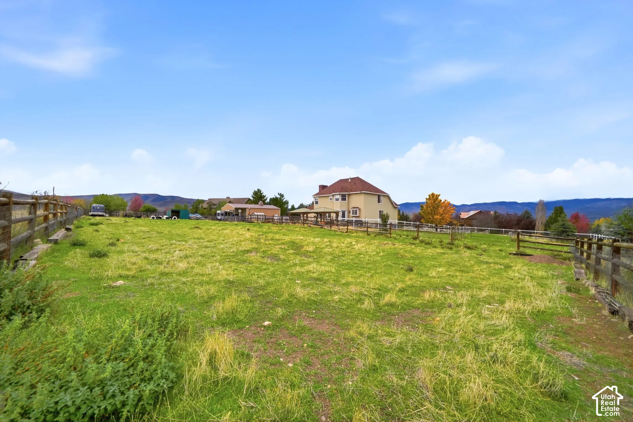 Expansive pasture featuring split-rail wood fencing and mountain silhouettes