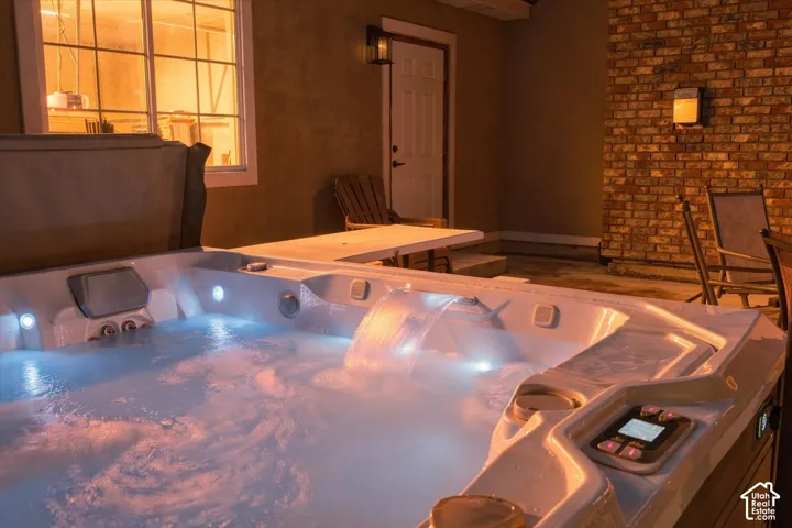 Built-in spa with integrated waterfall feature, exterior brick masonry detailing, and flush-mounted wall lighting