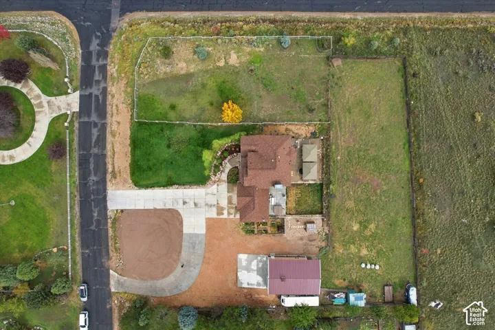 Aerial perspective featuring a multi-structure property with an expansive corner lot, concrete driveway, and established landscape