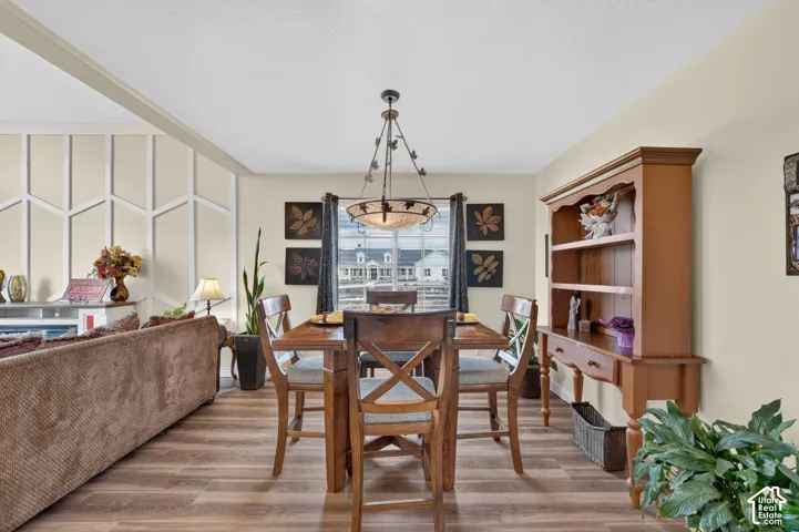 Dining area featuring wood-finish flooring, decorative wall paneling, and an overhead multi-light chandelier