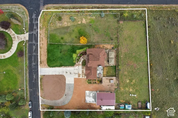 Aerial perspective of a sprawling lot featuring a multi-section roofline, expansive grounds, a concrete driveway, and dedicated hardscaped areas