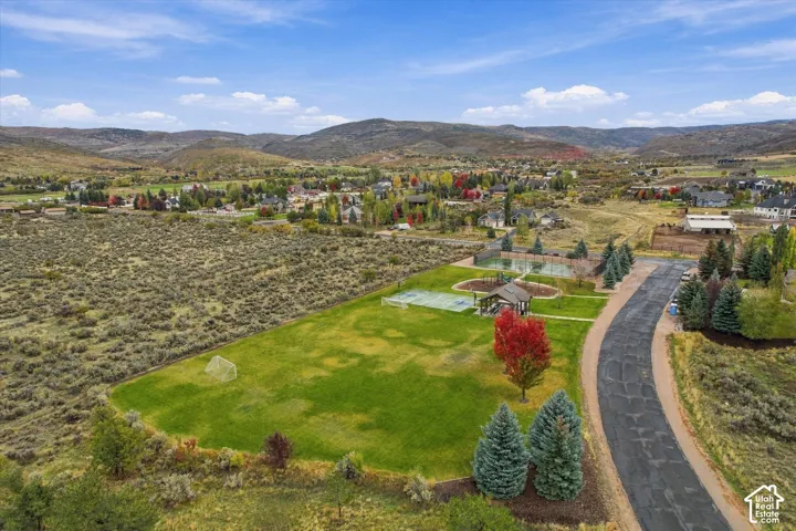 Expansive lot featuring a multi-sport court, a dedicated tennis court, a covered gazebo, and mountain scenery