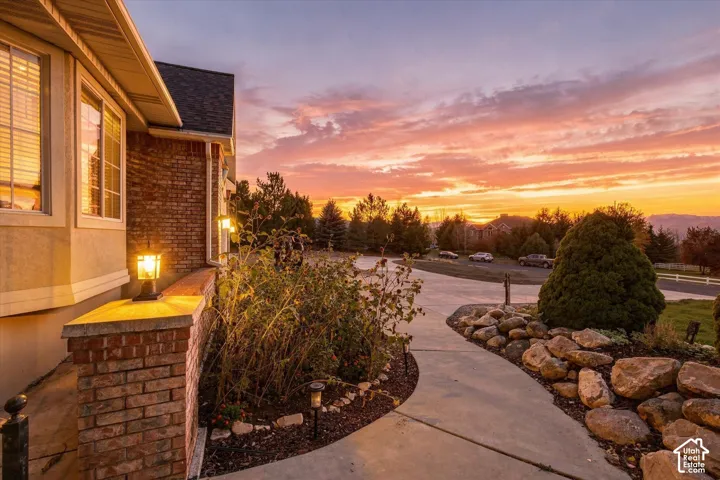 Exterior facade featuring brick masonry, multi-pane windows, stone hardscaping, concrete walkway, and built-in wall-mounted lighting