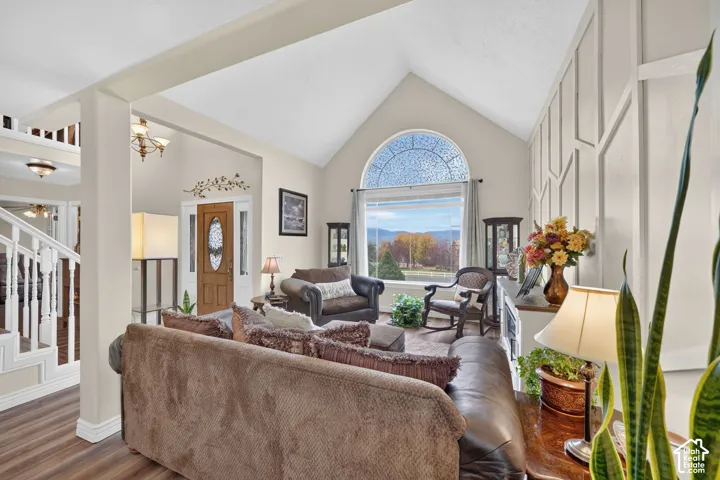 Vaulted ceiling, floor-to-ceiling geometric wall molding, arched window, wood-finish flooring, and grand staircase with white wood balusters