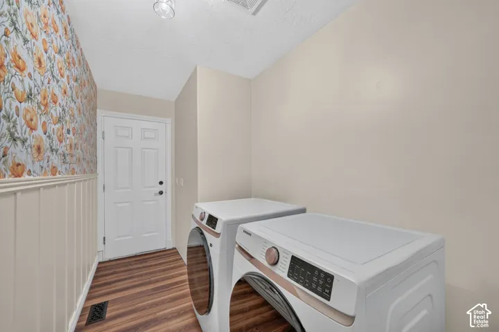 Laundry area featuring floral wallpaper, wood-finish flooring, and white wainscoting