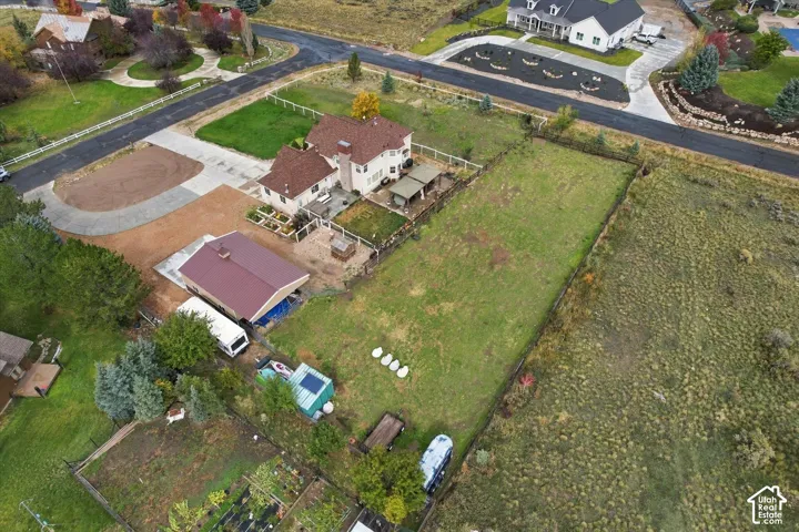 Expansive lot featuring a multi-story residence, a detached garage with a metal roof, a paved driveway, and perimeter fencing