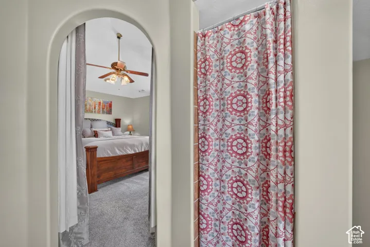 Arched doorway featuring a neutral wall finish and a multi-blade ceiling fan with integrated lighting