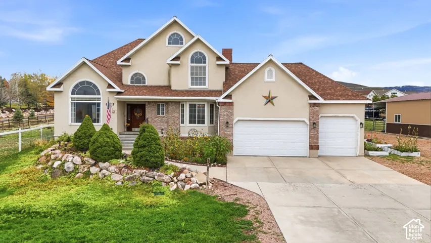 Multi-level exterior featuring stucco siding, brick accents, arched window detailing, a shingled roof, and a three-car garage