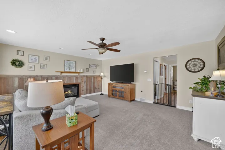 Living area featuring a fireplace with a wood-plank wall accent, recessed lighting, and a ceiling fan