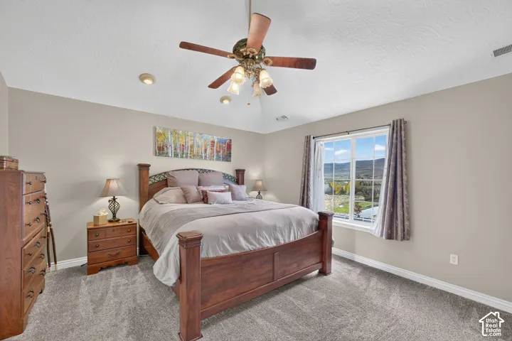 Vaulted ceiling with an integrated multi-light ceiling fan, neutral wall tones, wall-to-wall carpeting, and a double-pane window featuring mountain scenery