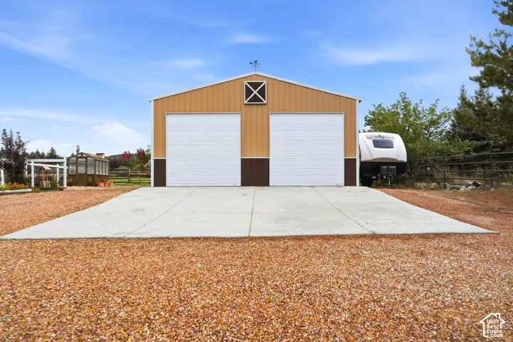 Detached two-car garage featuring metal siding, a concrete apron, and a gable roof with a decorative cupola