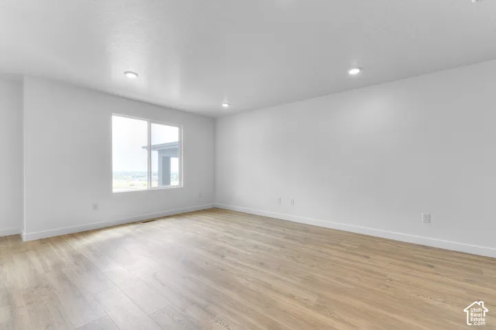 Spacious room featuring wood-finish flooring, recessed lighting, and a window with exterior sightlines