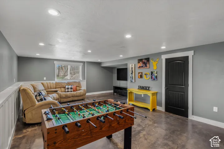 Neutral-toned interior space featuring recessed ceiling lighting, concrete flooring, crisp white millwork, and a solid-core interior door with decorative molding