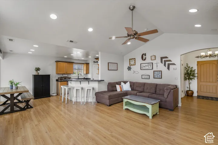 Vaulted ceilings with recessed lighting, wood-finish flooring, breakfast bar, and an arched entryway