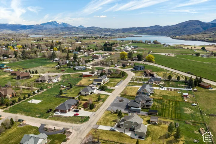 Aerial perspective of a residential neighborhood featuring mountain topography, expansive open terrain, and proximity to a large body of water