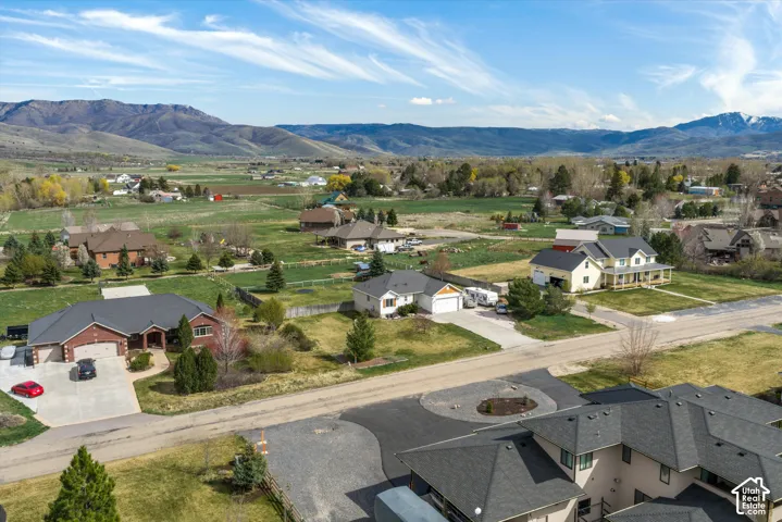 Aerial perspective of a multi-structure residential area featuring asphalt roofing, concrete driveways, and expansive mountain terrain