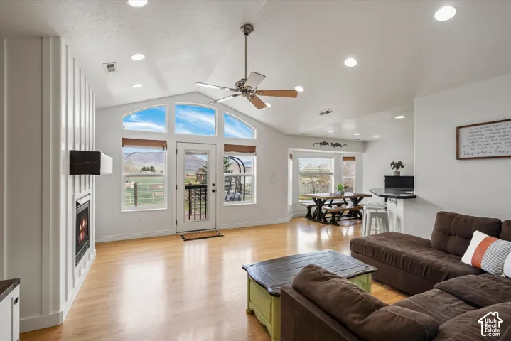 Vaulted ceilings, wood-finish flooring, recessed lighting, floor-to-ceiling vertical paneled wall, and a built-in fireplace with a stone-surround facade