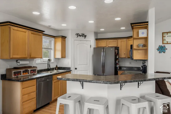 Kitchen featuring wood cabinetry with crown molding, laminate countertops, a breakfast bar, recessed lighting, and a pantry with a paneled door