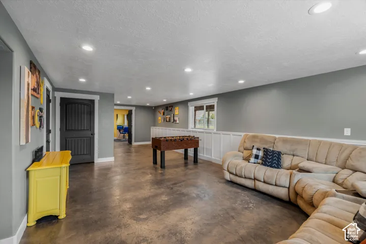 Spacious room featuring polished concrete flooring, recessed lighting, white wainscoting, and a multi-panel interior door