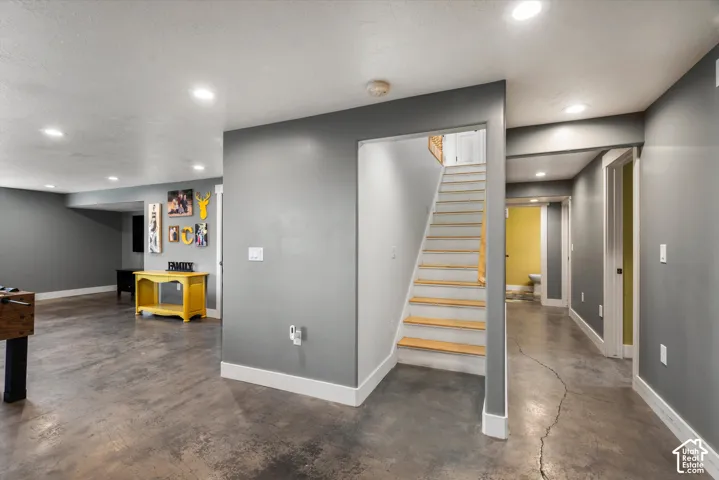 Interior space featuring polished concrete flooring, recessed lighting, and a staircase with light-toned wood-finish treads