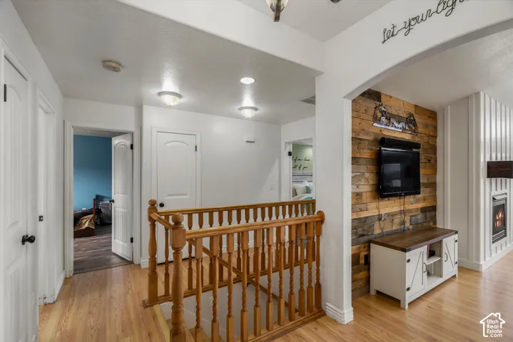 Wood-finish flooring, staircase with a wood balustrade, wood-plank accent wall, and vertical paneling