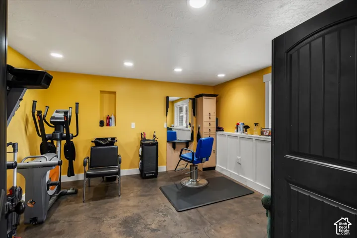 Interior room featuring polished concrete flooring, recessed ceiling lighting, a built-in wall niche, wainscoting, and a solid black paneled door