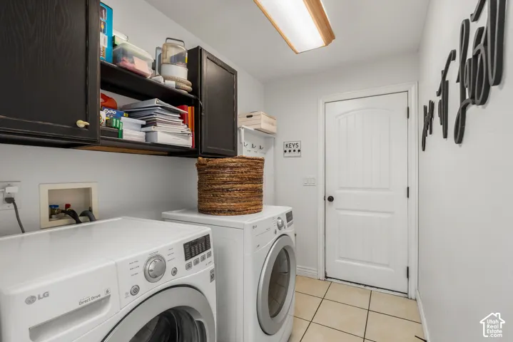 Utility room featuring dark-finish upper cabinetry, recessed lighting, tile flooring, and an arched-panel interior door